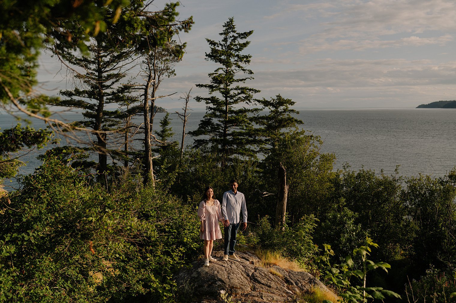 Couple on granite oceanfront bluffs overlooking Howe Sound and the Pacific Ocean at Whytecliff Park in West Vancouver BC